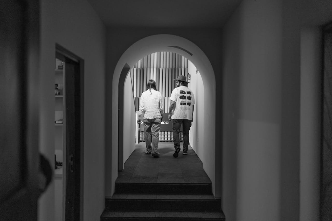 heros-img Two adults walking down a corridor under an arch in a black and white photograph.